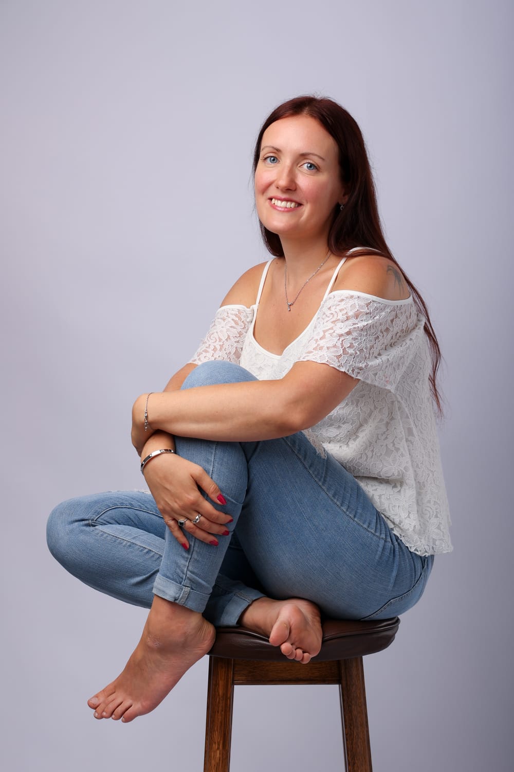 Jonnah Stark sitter leende på en pall i jeans och vit spetstopp
