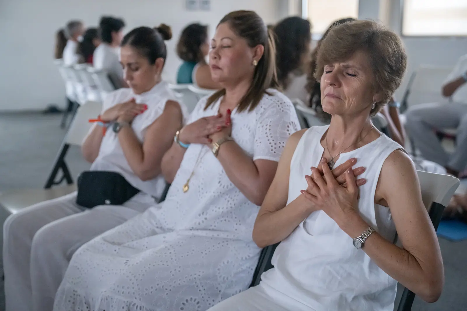 Participantes con las manos en el corazón y los ojos cerrados