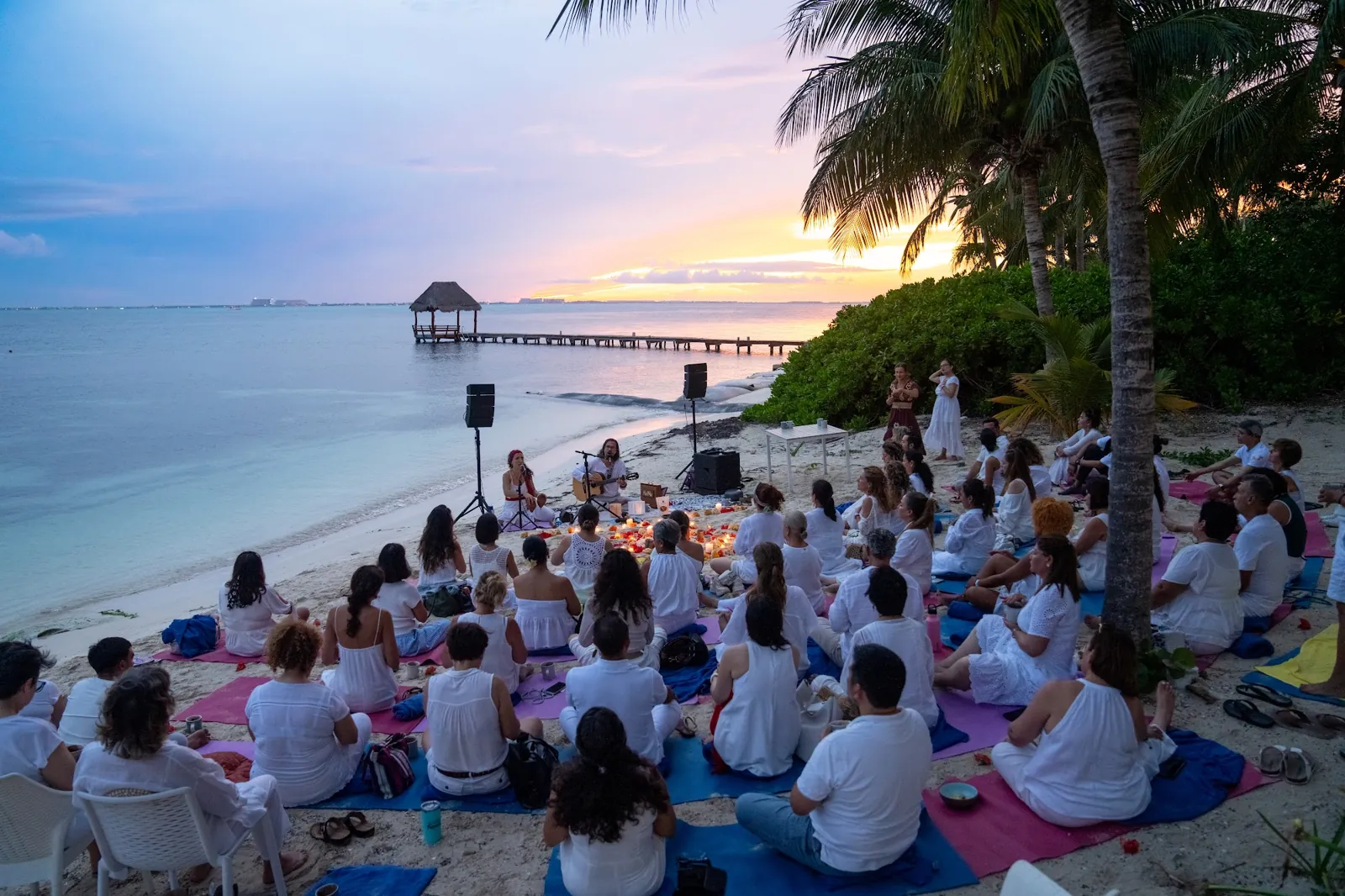 Un grupo del retiro En Unidad meditando en círculo en la playa al atardecer, frente al Caribe (Cancún 2025)