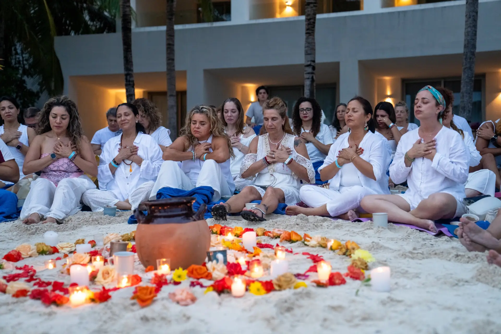 Círculo de meditación en la playa, vestidos de blanco y con las manos en el corazón, retiro En Unidad Cancún 2025