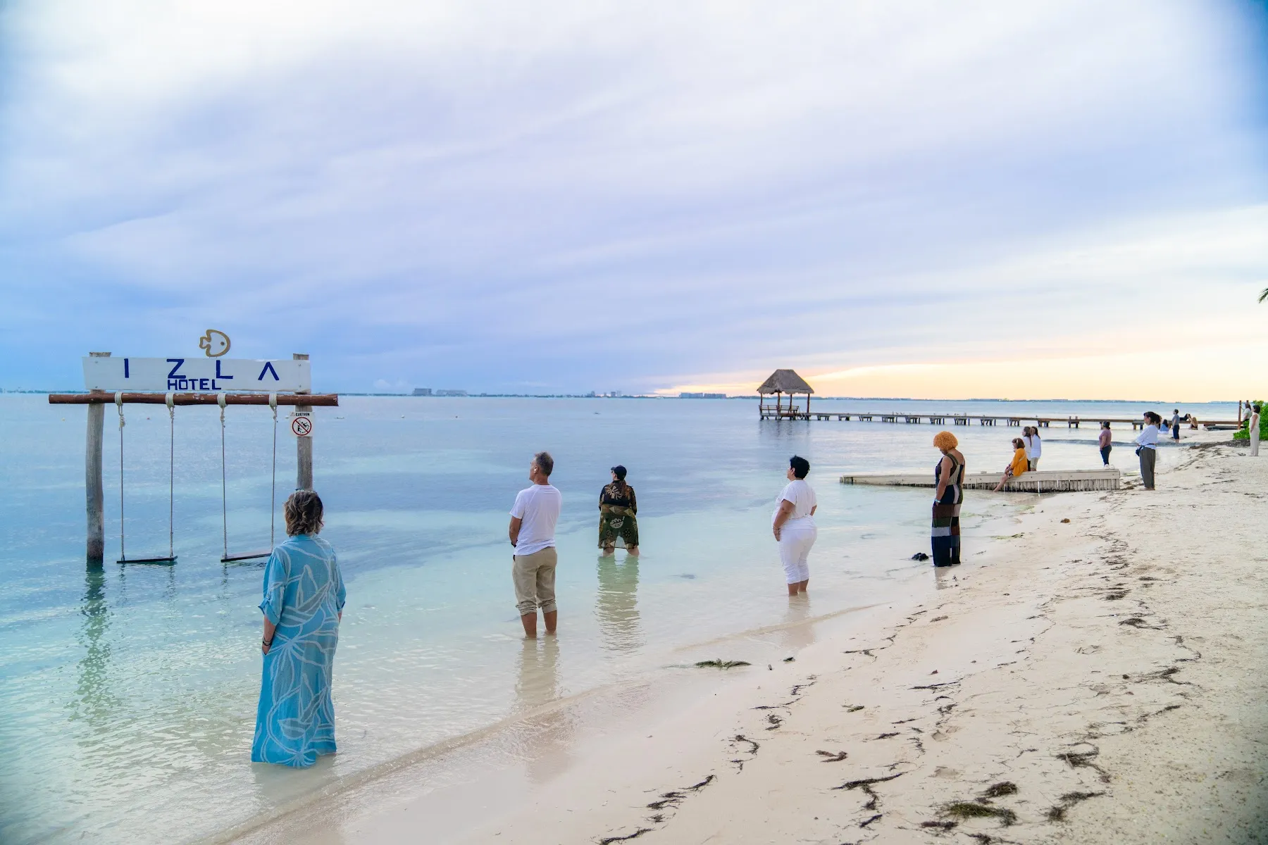 Participantes de pie en el mar al amanecer durante una meditación caminando, retiro En Unidad Cancún 2025