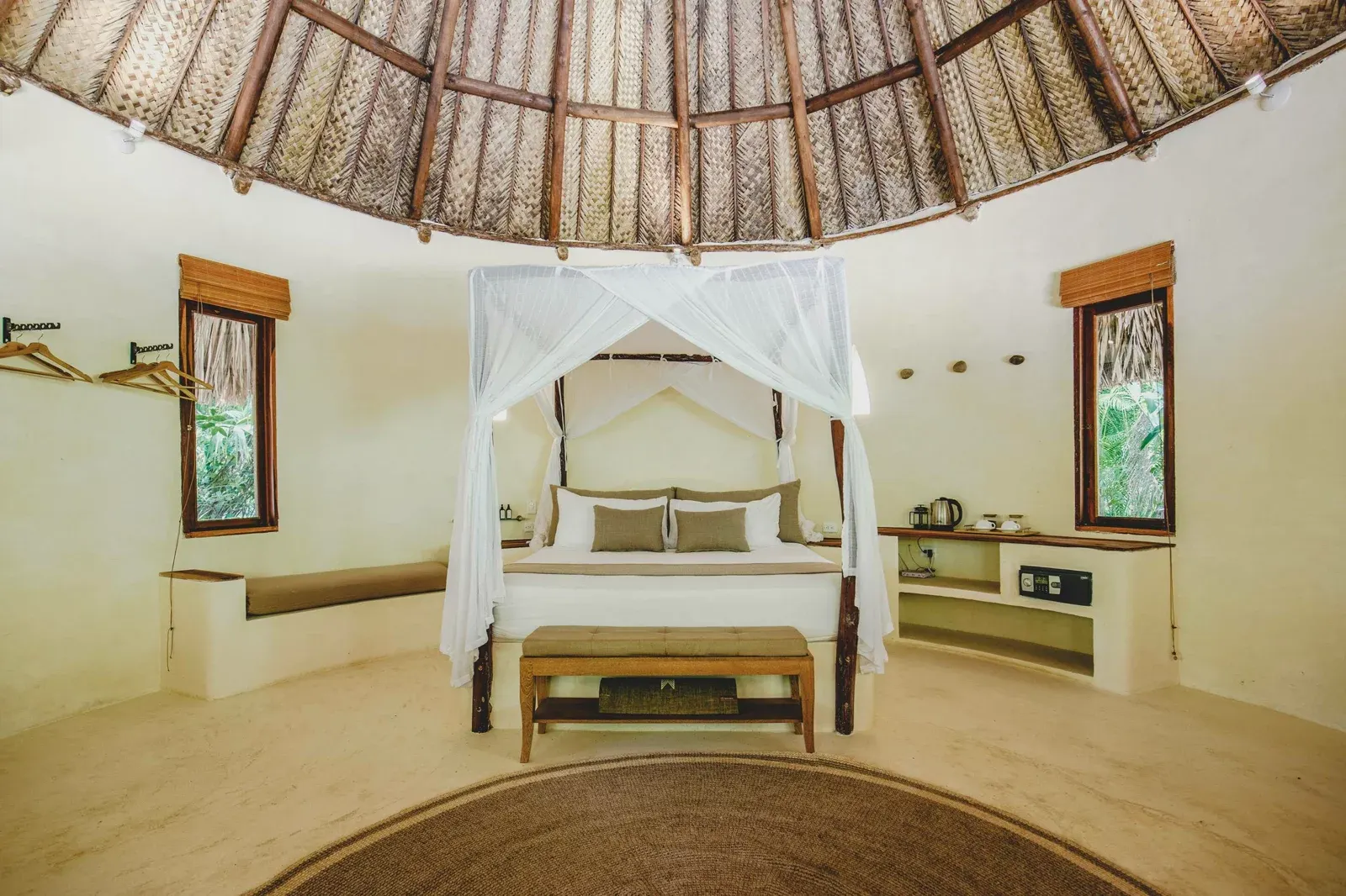 Cabaña Queen con cama con dosel blanco y techo de palma