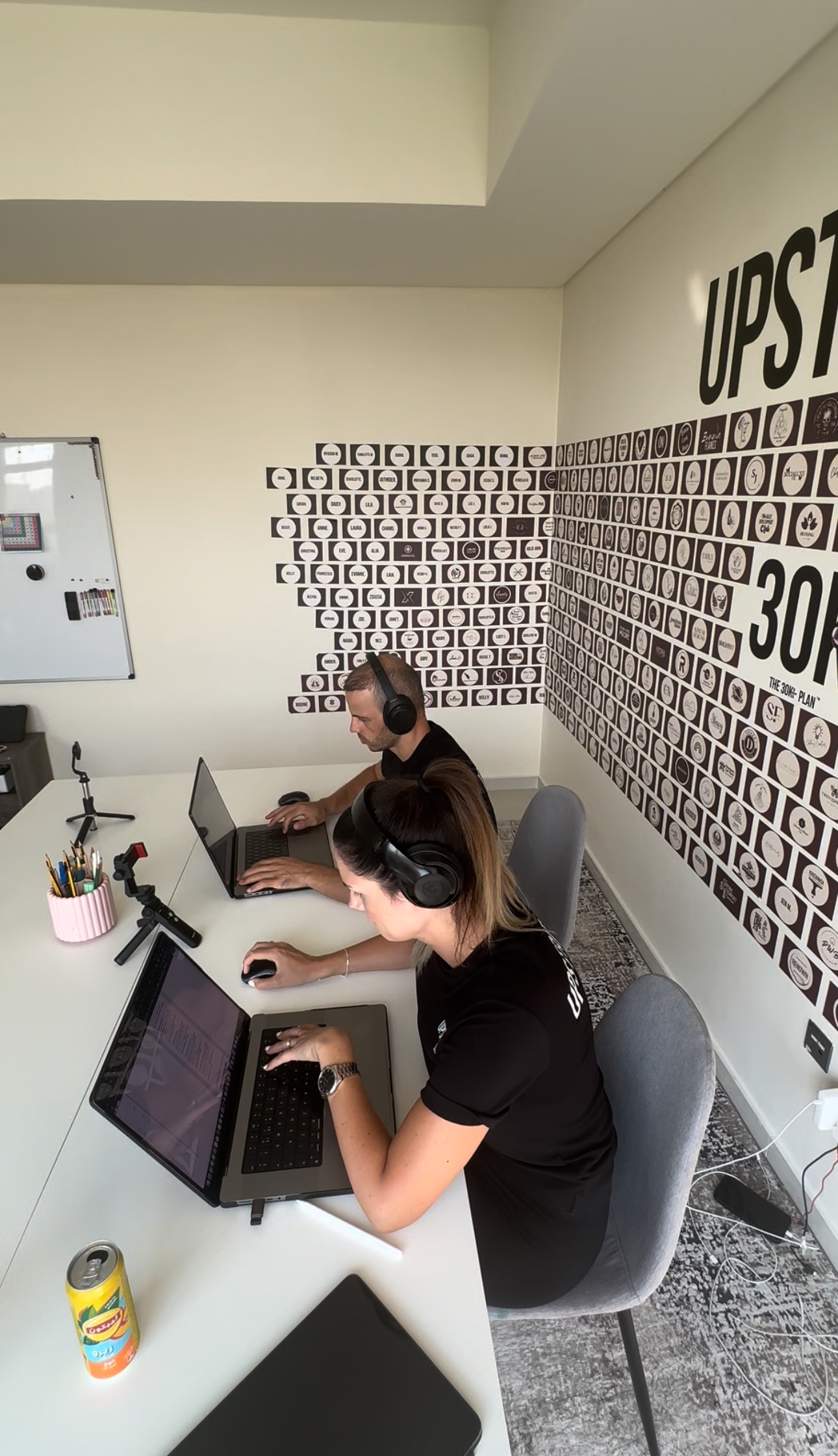 Upstrider team working side by side in their Dubai office, focused on laptops with client planning boards on the wall.