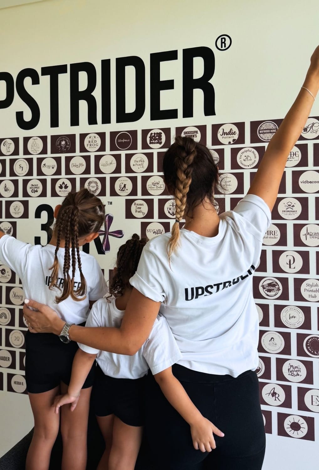Anne and daughters in front of member wall