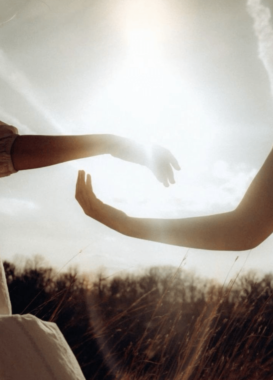 Two hands reaching toward each other in golden light