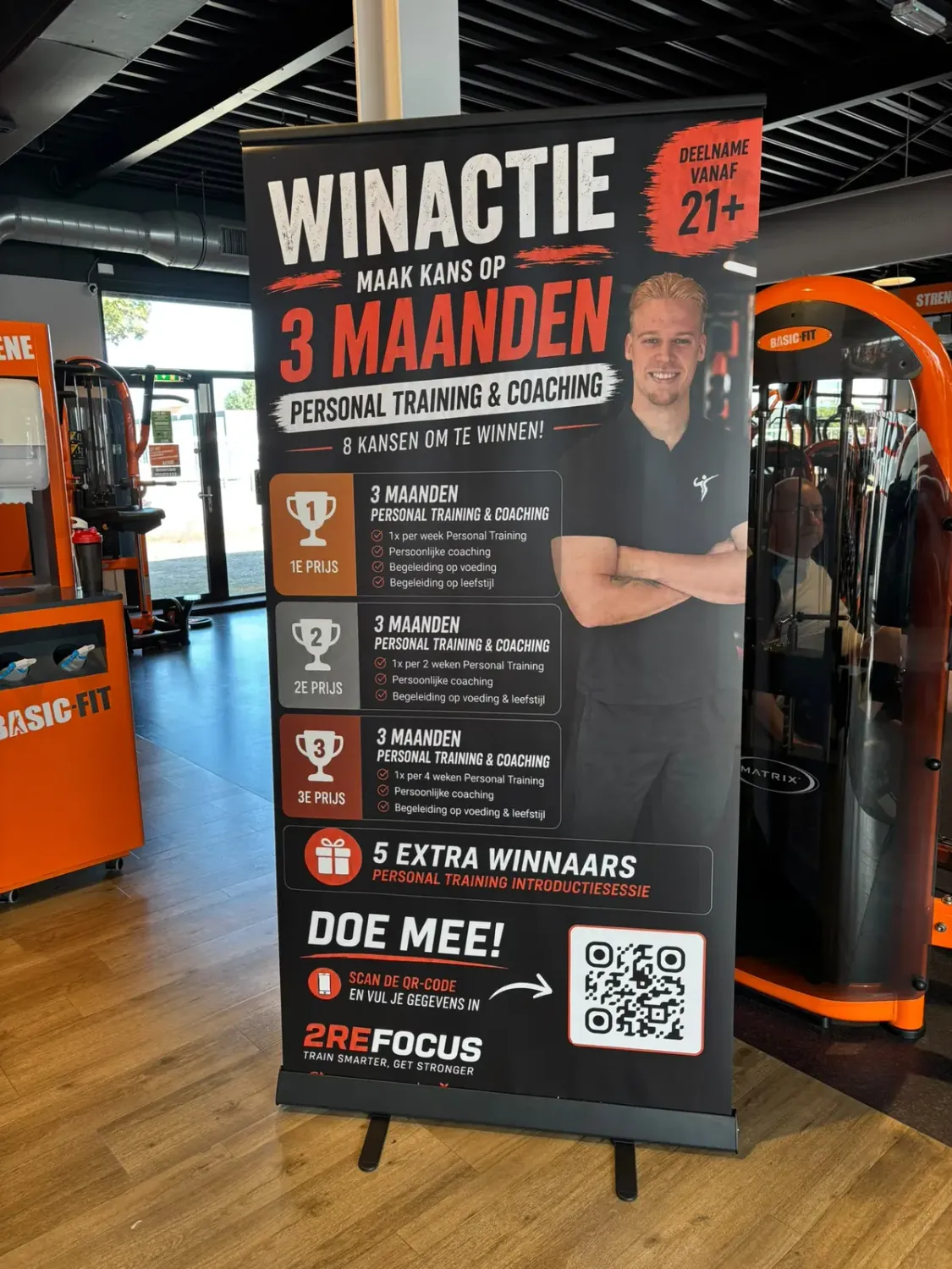 Banner van een 2Refocus-trainer met winactie en QR-code in de Basic-Fit