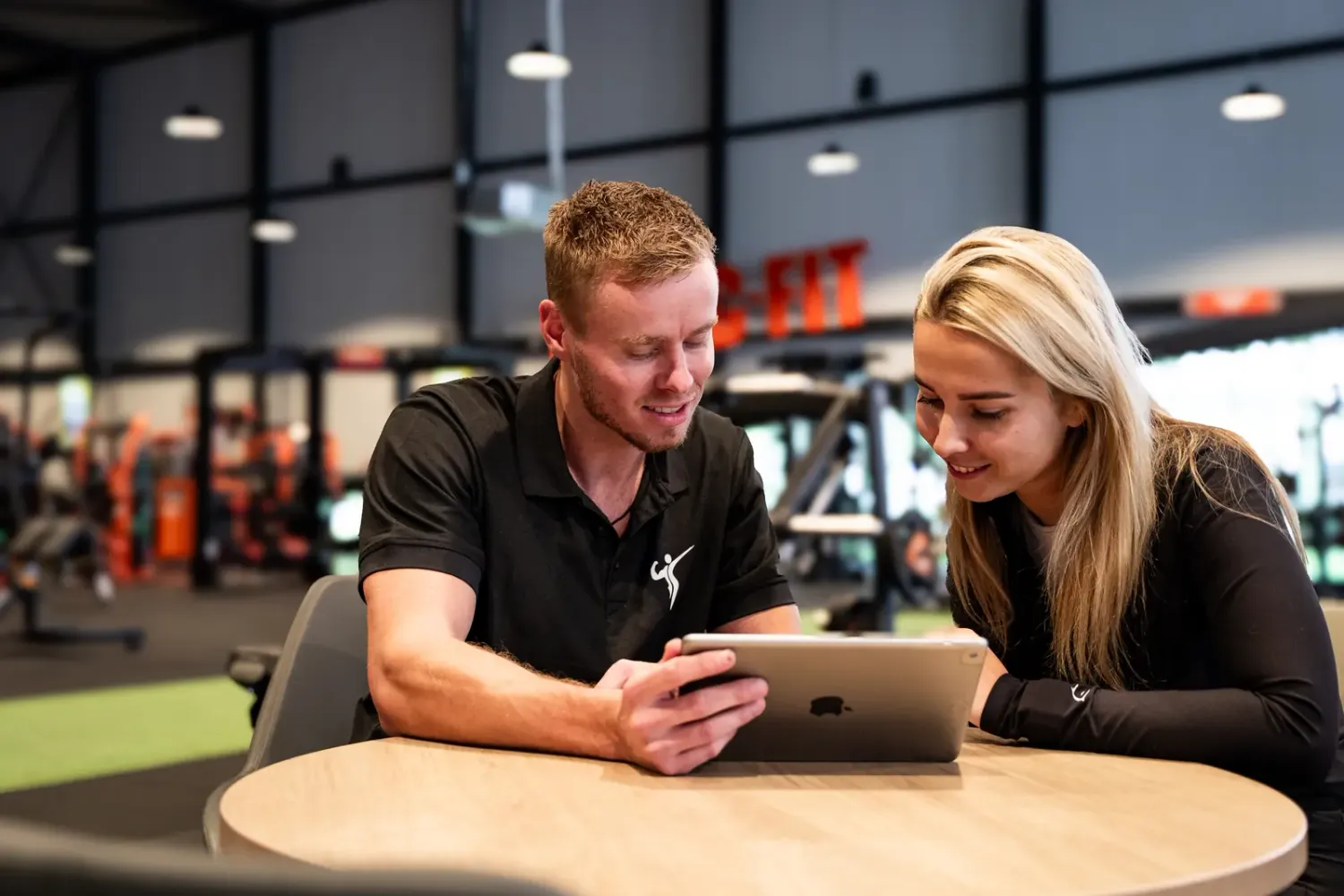 Trainer en klant bekijken samen het trainingsschema op een tablet