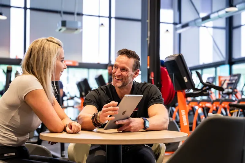 Kennismakingsgesprek met een trainer aan tafel in de Basic-Fit