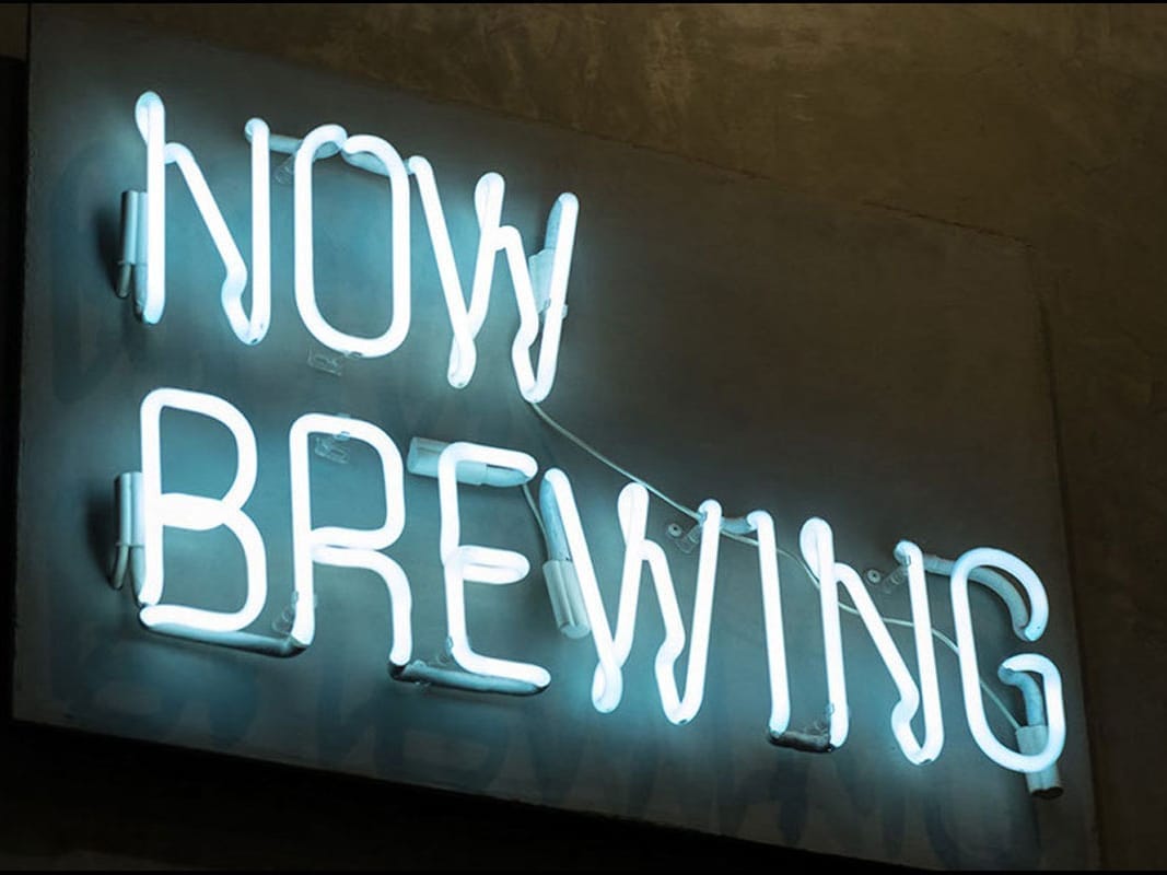 Neon sign reading “Now Brewing” – Cold Brew Coffee Lab marketing sho