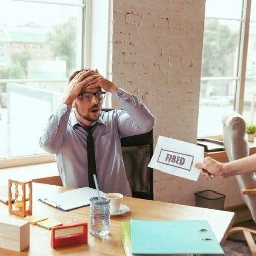 Young businessman fired, looks upset. Has to pack his office belongings and to leave work place for new worker.