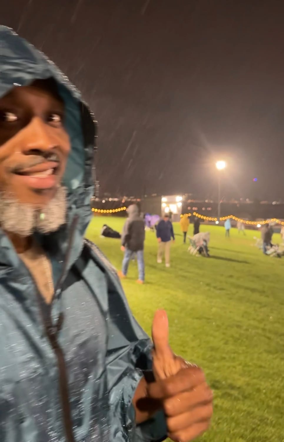 man smiling standing in the rain wiht a raincoat smiling at an outdoor event, making life an occasion.