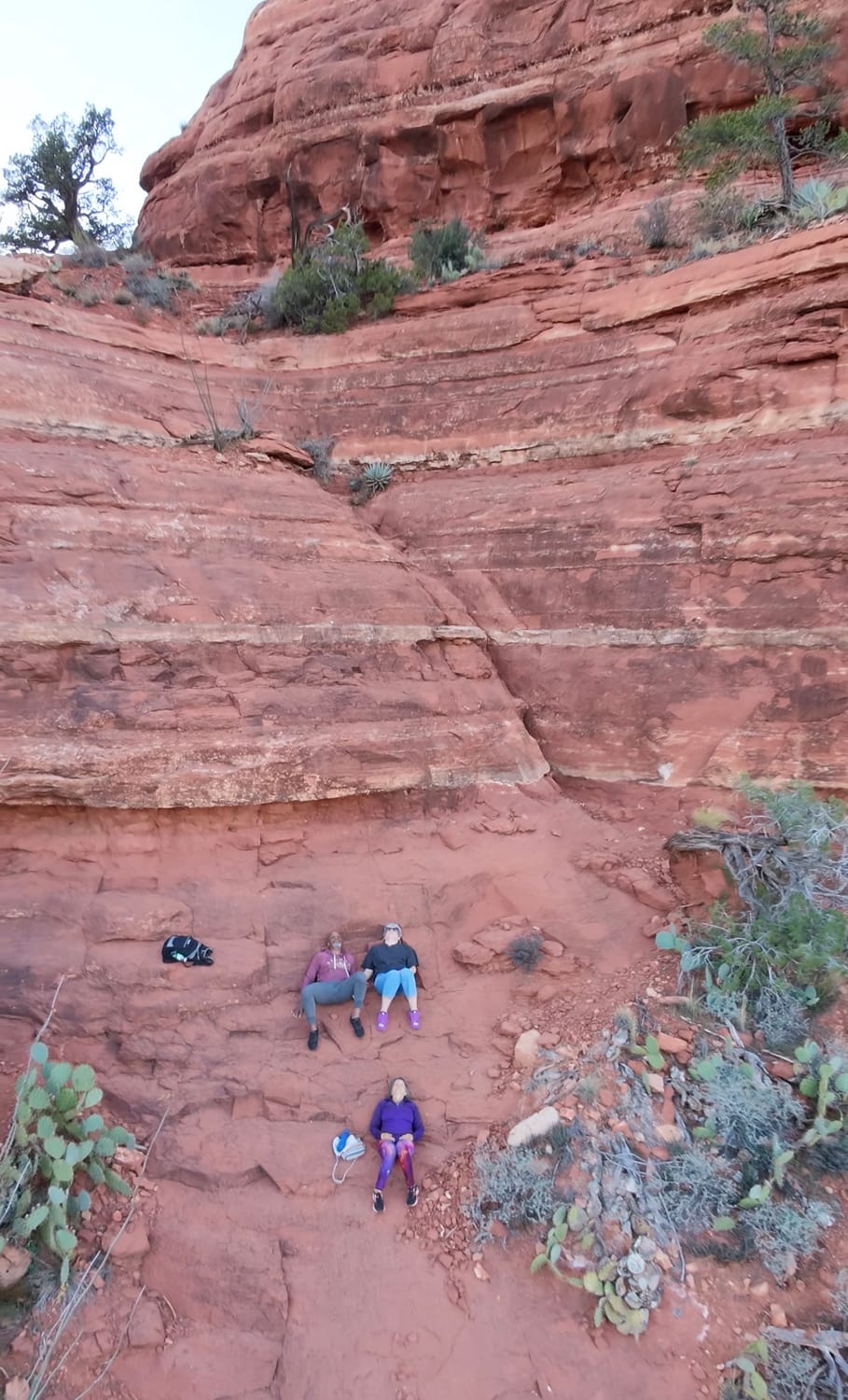 three people connecting laying on their backs on the red rock kachina women in Sedona making life an occasion