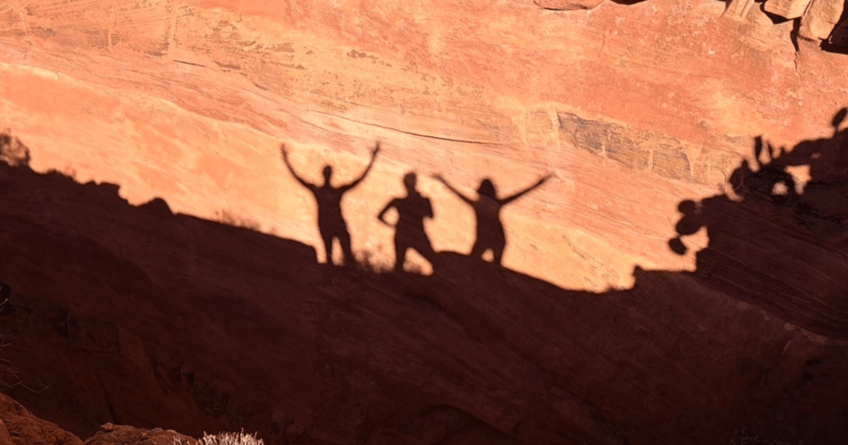 Silhouettes of people celebrating on Sedona red rocks during a storytelling videography experience, making life an occasion.