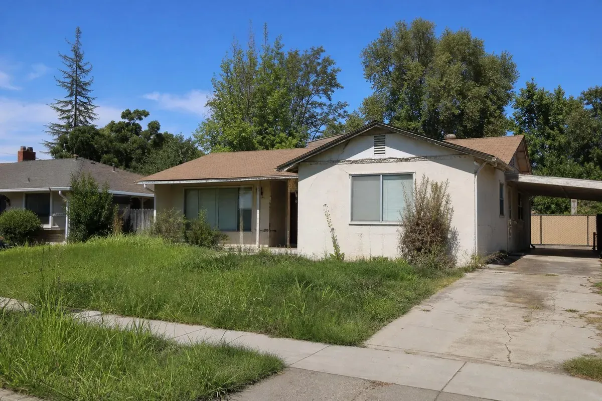 A modest single-story house with an overgrown lawn, the kind of property where an owner may be behind on taxes