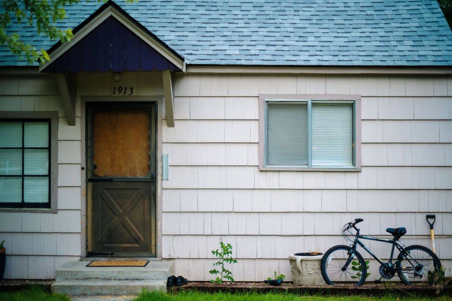 Older house with tired siding and a worn front door in Plano