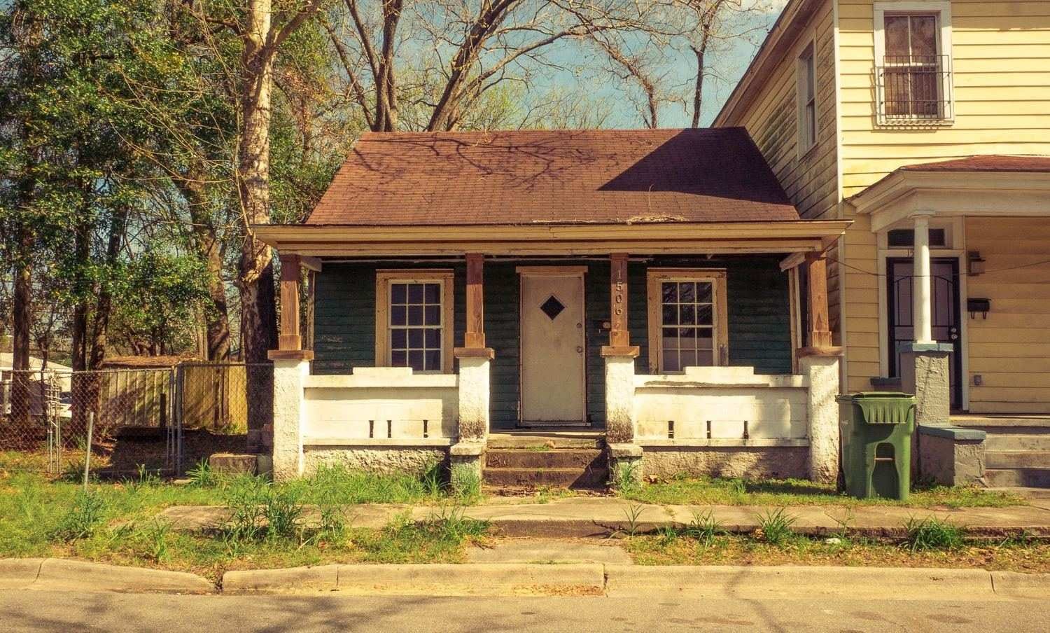 Older bungalow with a worn front porch in Plano, TX