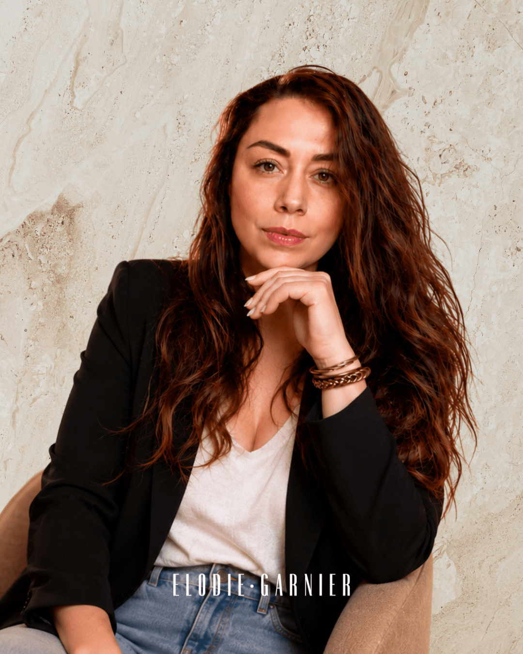 Élodie Garnier, assise dans un fauteuil, en blazer noir