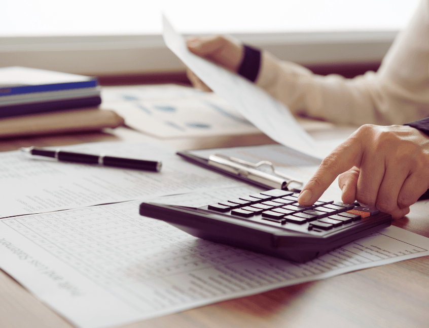 Femeie care ține bancnote de 100 de dolari, alături de o pușculiță roz pe masă – simbol al veniturilor pasive și al creșterii financiare fără efort suplimentar.