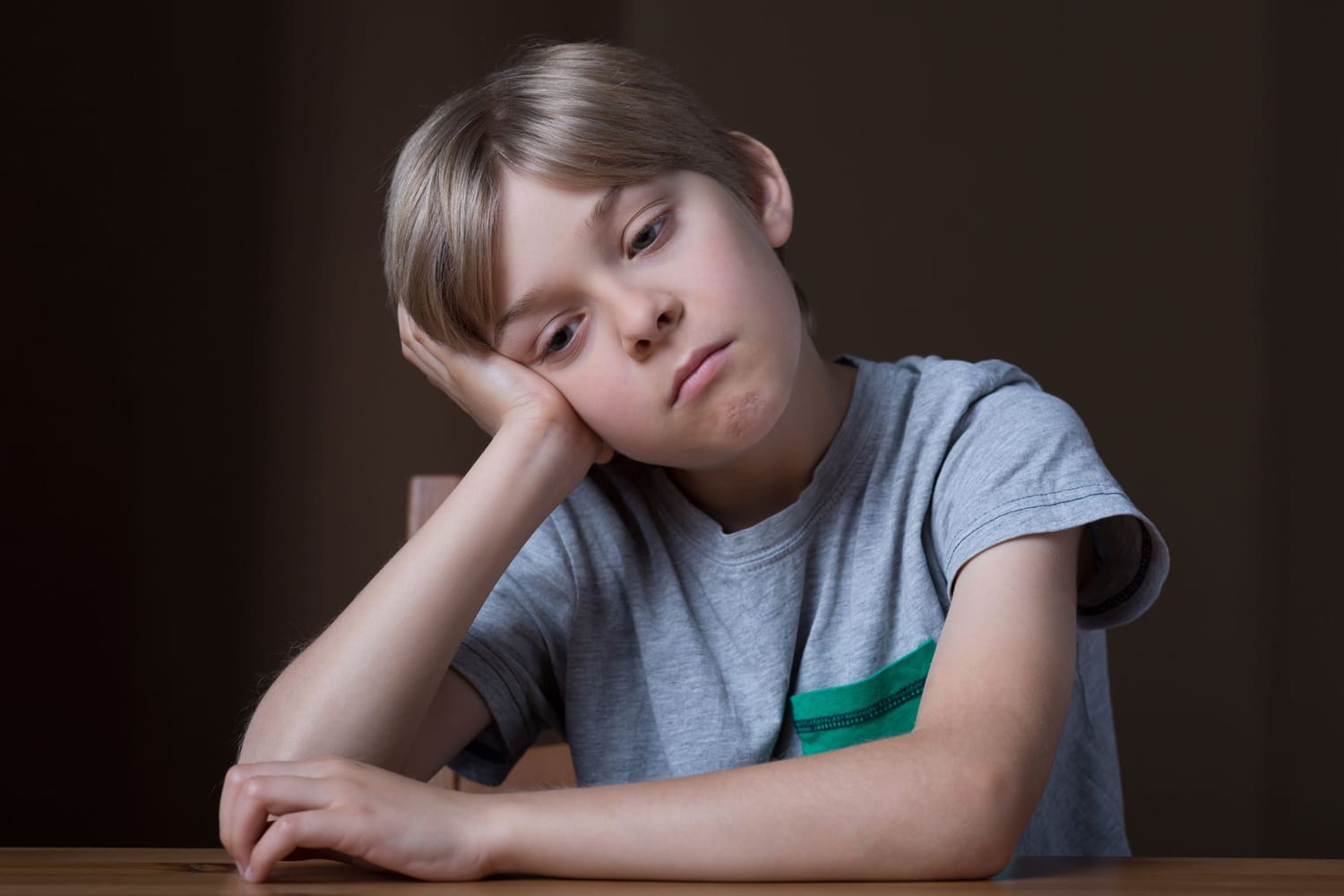 Un enfant seul dans une cour d'école, l'air inquiet