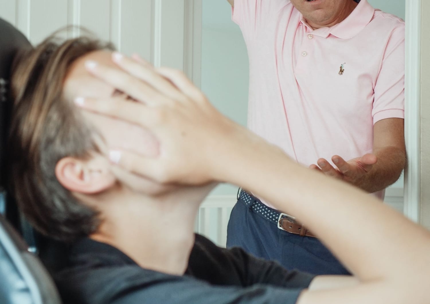 un ado se tient le visage car il est énervé par son père. Il se plaint de maux de ventre
