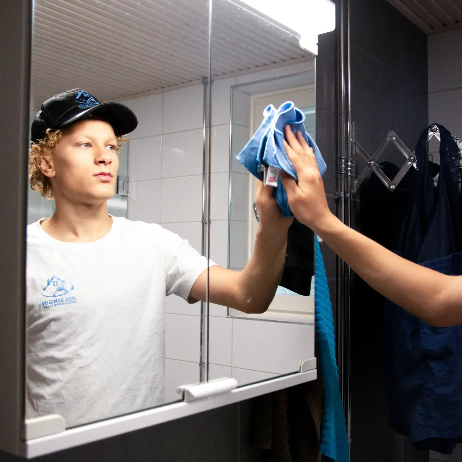 Siivoja taittamassa vaatteita valkoisen sängyn päällä