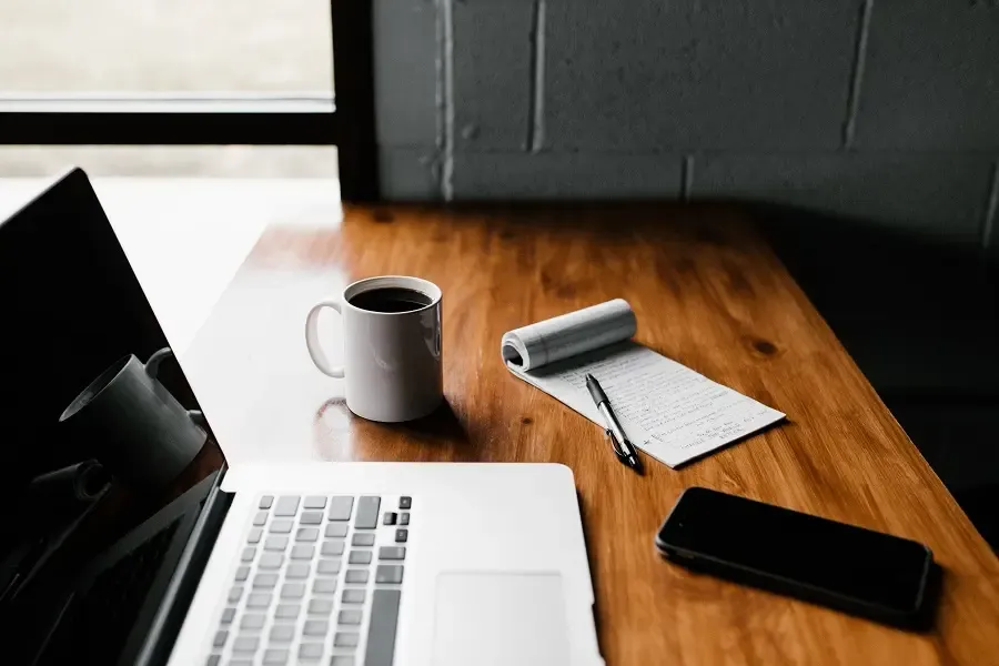 Open laptop, notebook, and coffee cup on a wooden desk – ready for focused work or a relaxed connection chat.