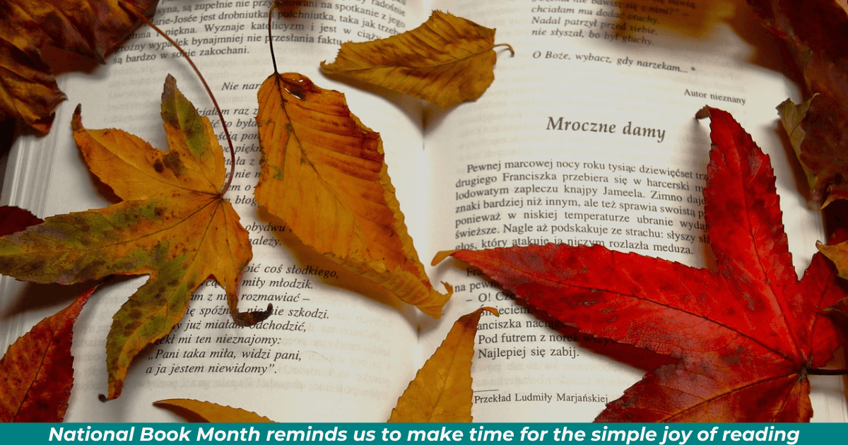 A fall setting with autumnal leaves in jewel-tone colors lying atop an opened book. The caption reads, "Nation Book Month reminds us to make time for the simply joy of reading."