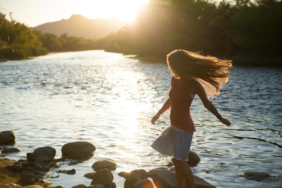 Femme libérée dansant dans une rivière au soleil, libération des blocages