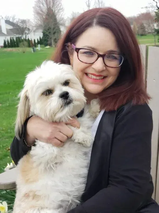 Coach Colette holding her adorable dog in their backyard.