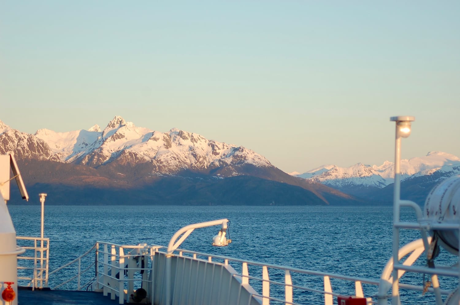 Small boat navigating a Patagonian fjord toward a blue glacier face