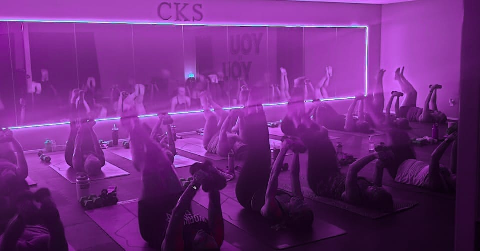 Yoga class in a dark-lit studio glowing with purple LED lights at Crystallyn Kay’s Studio
