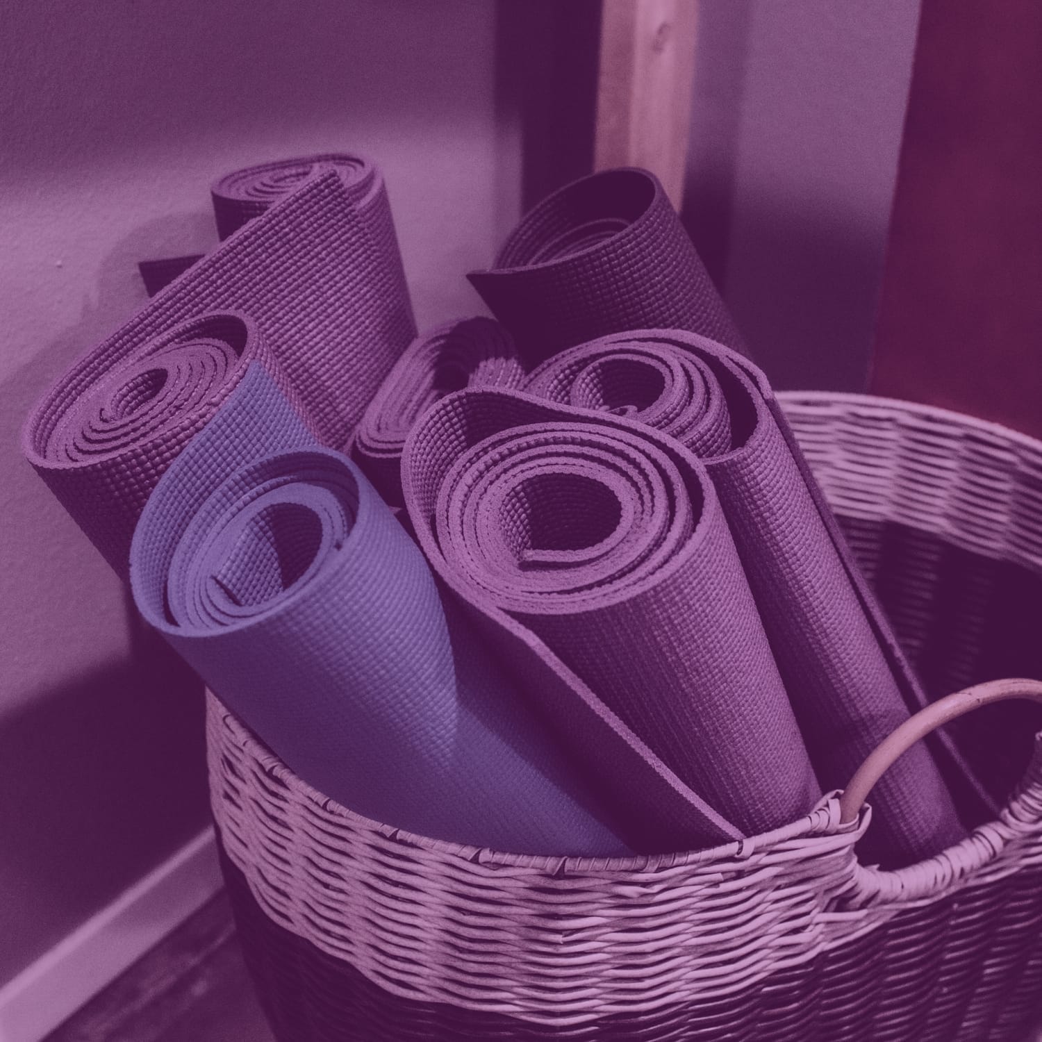 Rolled yoga mats neatly organized in a wicker basket inside the studio