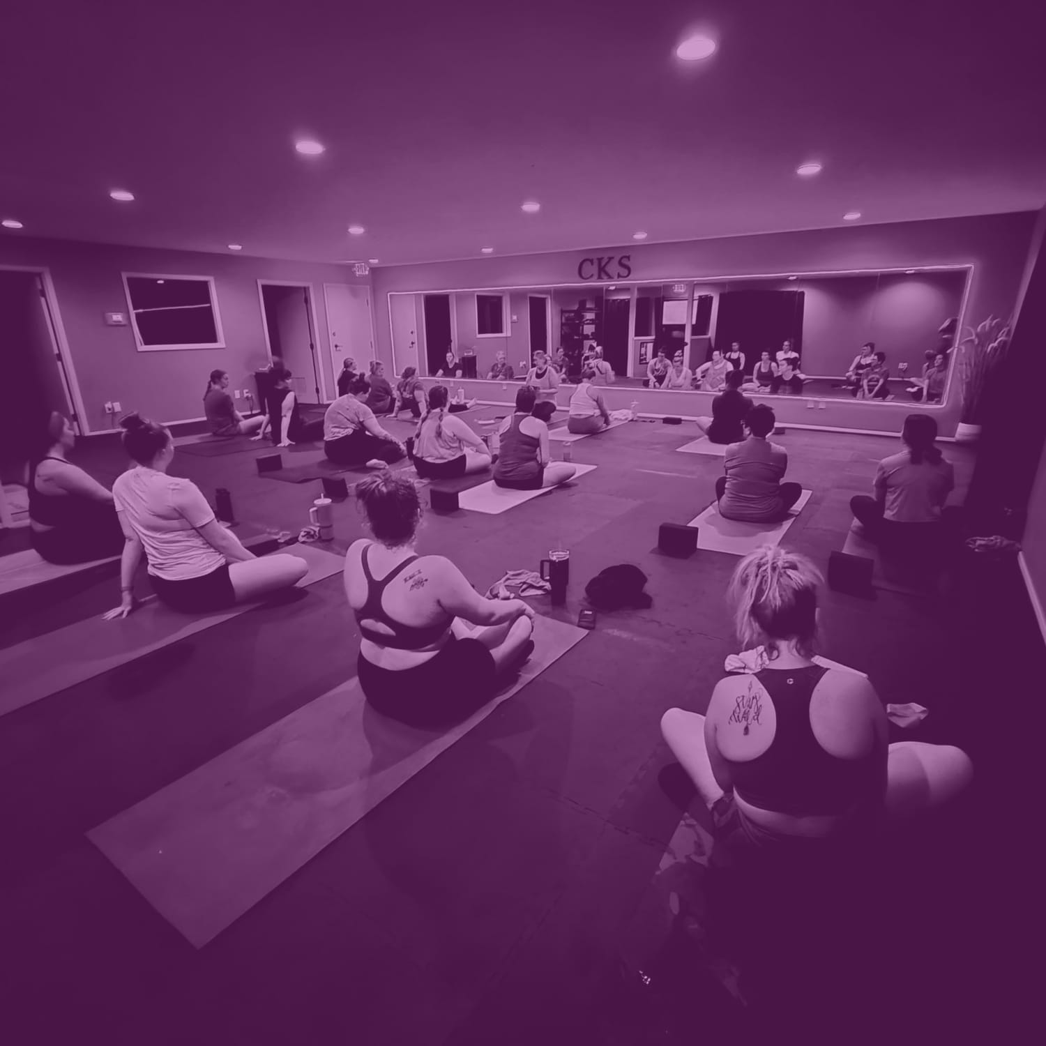 Yoga sculpt class in session with students on mats facing the instructor under soft studio lighting