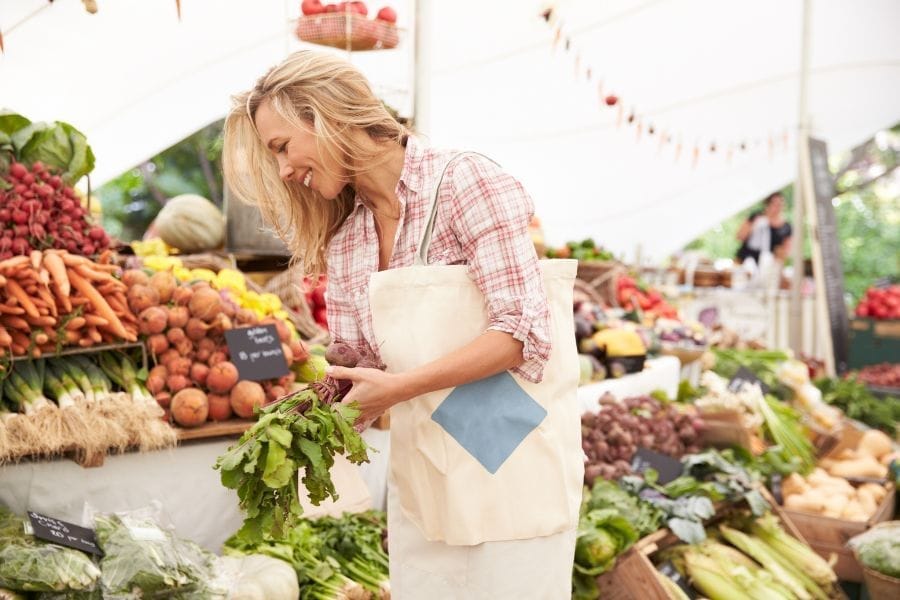 Femme qui achète des légumes frais au marché