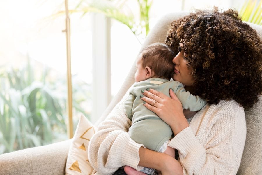 Maman assise dans un fauteuil avec bébé dans ses bras