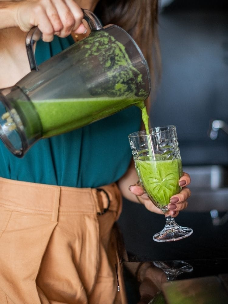 Femme qui se sert un jus détox vert
