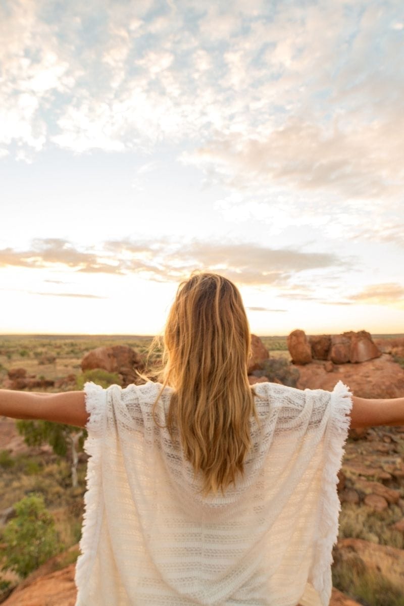 Femme blonde qui ouvre les bras vers le ciel lumineux