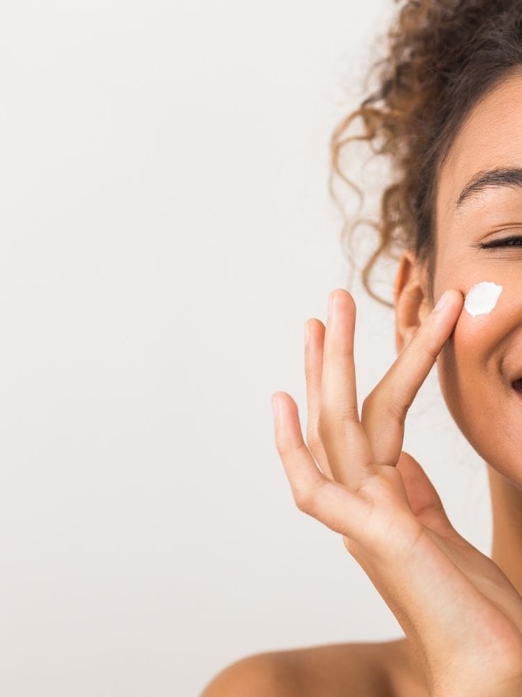 Femme moitié de visage avec crème sur la joue