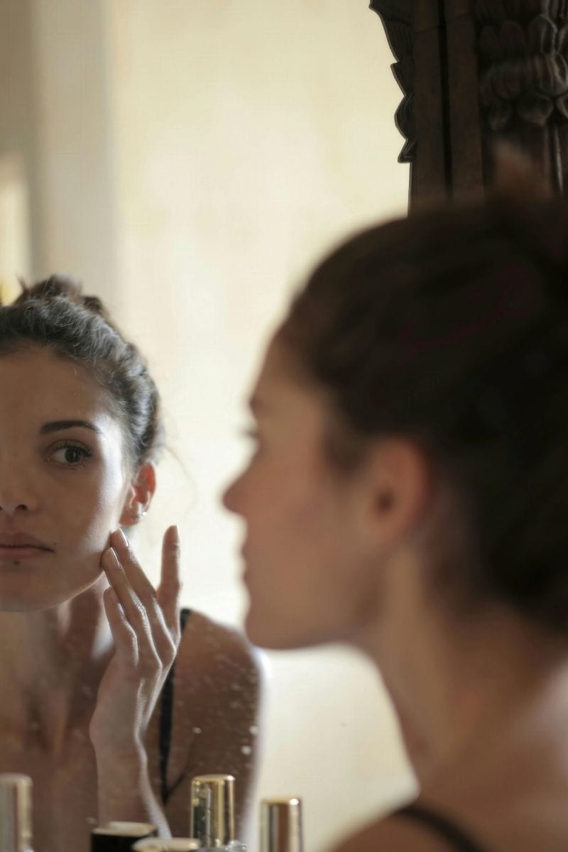 Femme regarde sa peau atopique devant le miroir