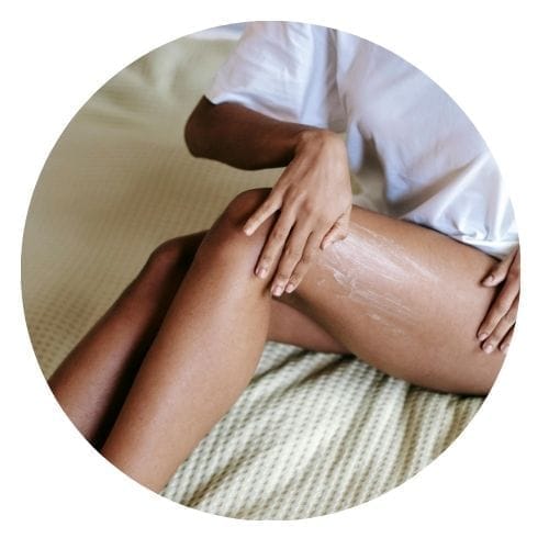 Femme qui s'applique une crème sur sa jambe