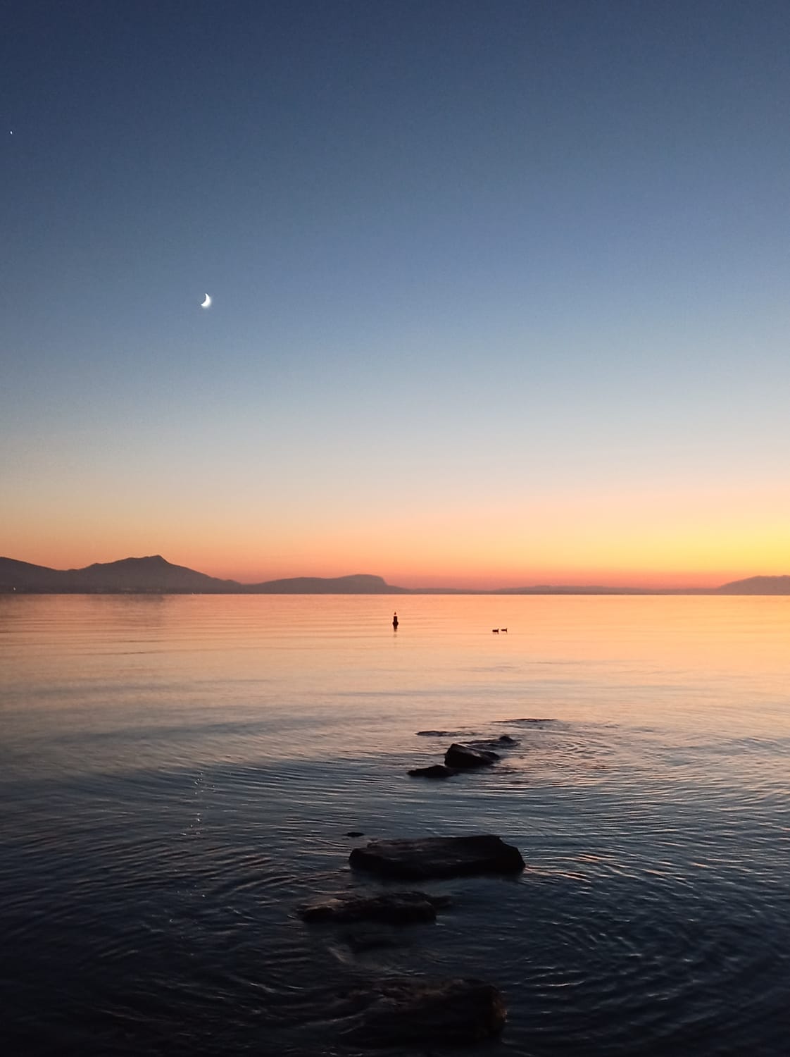 Coucher de soleil sur le lac, des pierres qui avancent dans l’eau