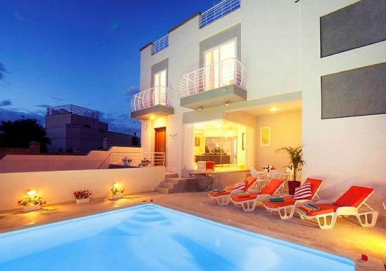 villa vue extérieure avec piscine et transats