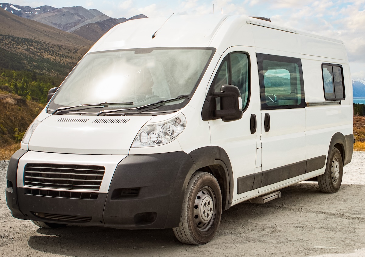 White campervan parked beside a scenic lake in New Zealand.