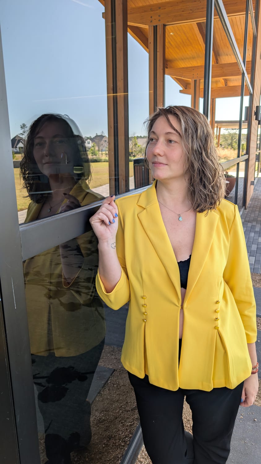 Anna Bohuslavska, inner guide for conscious moms, standing beside a glass window, her reflection looking back at her