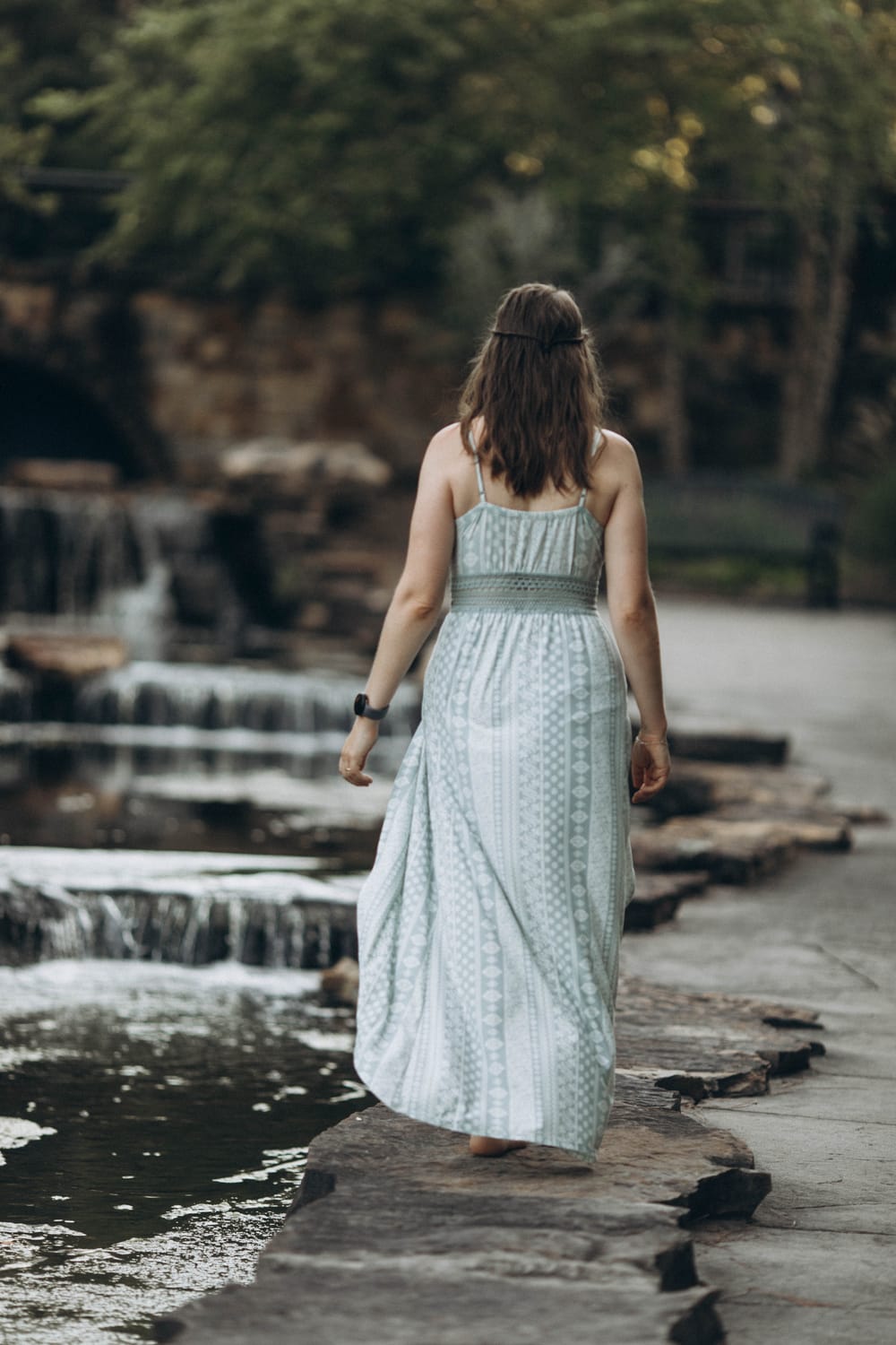 Anna Bohuslavska, inner guide for conscious moms, walking barefoot along a stone path beside small waterfalls