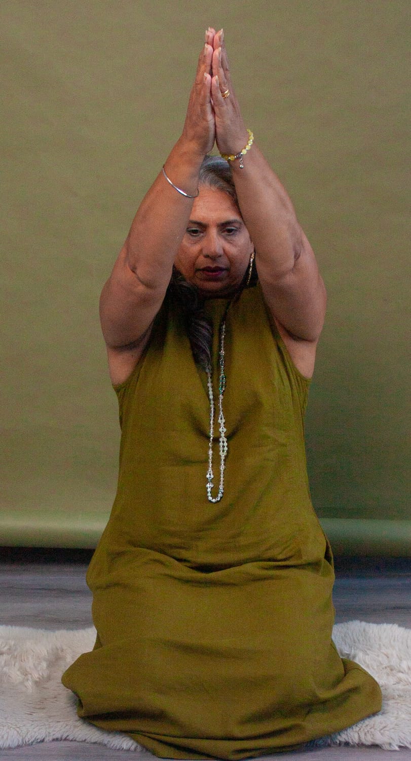Harjit guiding a Kundalini yoga breath practice, arms raised