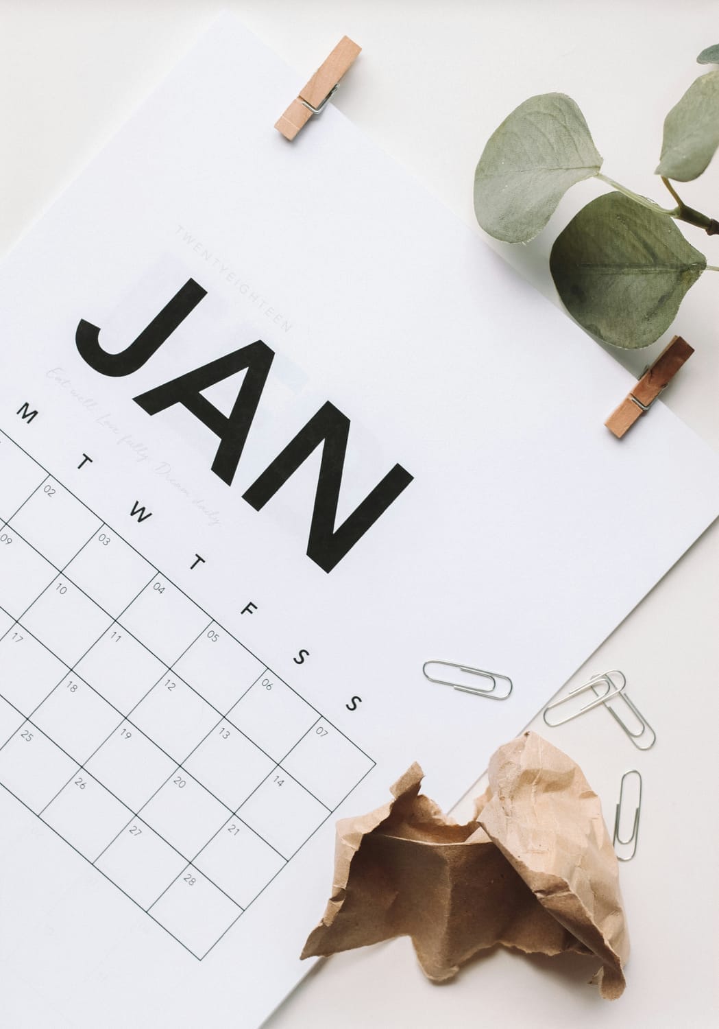 Calendrier de janvier posé sur un bureau avec des feuilles et des accessoires, illustrant la planification des publications pour artisans et commerçants