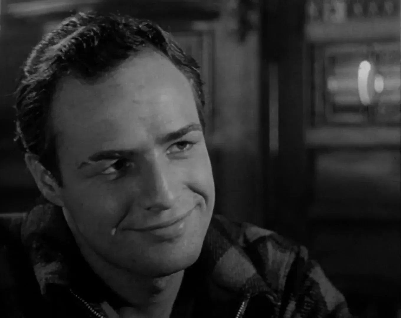 Marlon Brando nel ruolo di Terry Malloy, in primo piano con un mezzo sorriso, in Fronte del porto