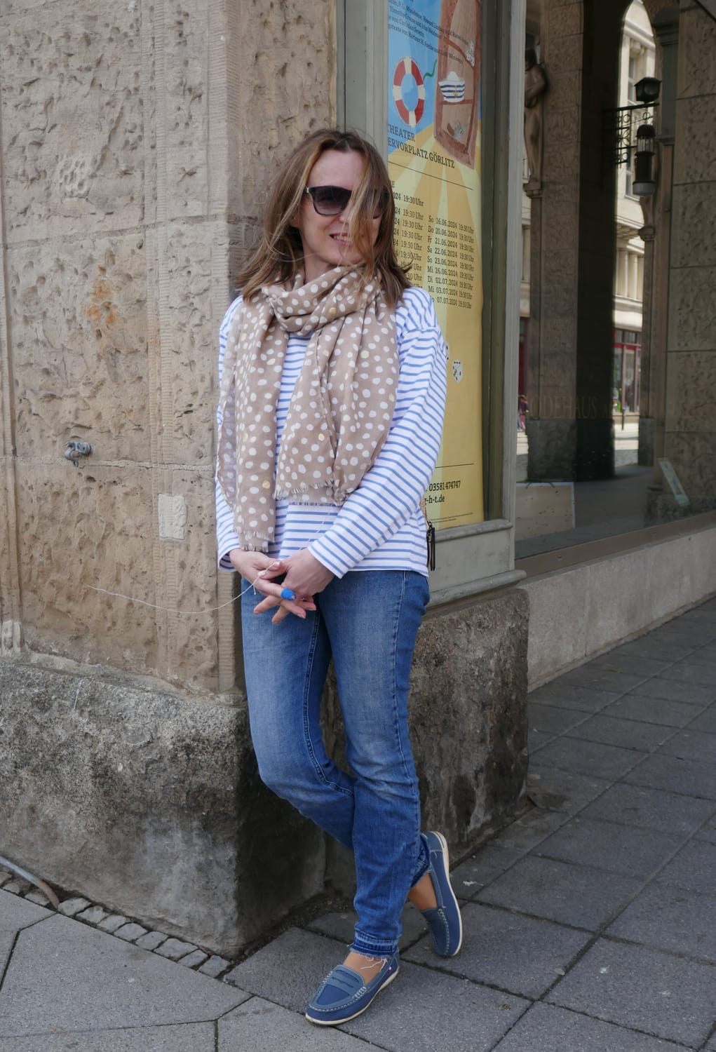 a woman in a blue jeans and stripy blue-white  top smiling at the camera 