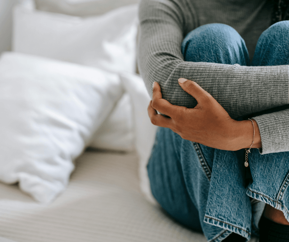 A DETAIL OF WOMAN BODY SITTING AND HOLDING HERSELF IN PAIN 